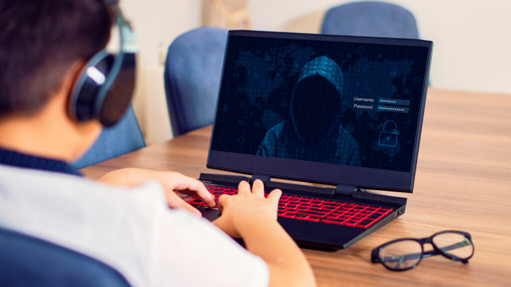 Ung mann med headset ser på pc med hacker på skjermen