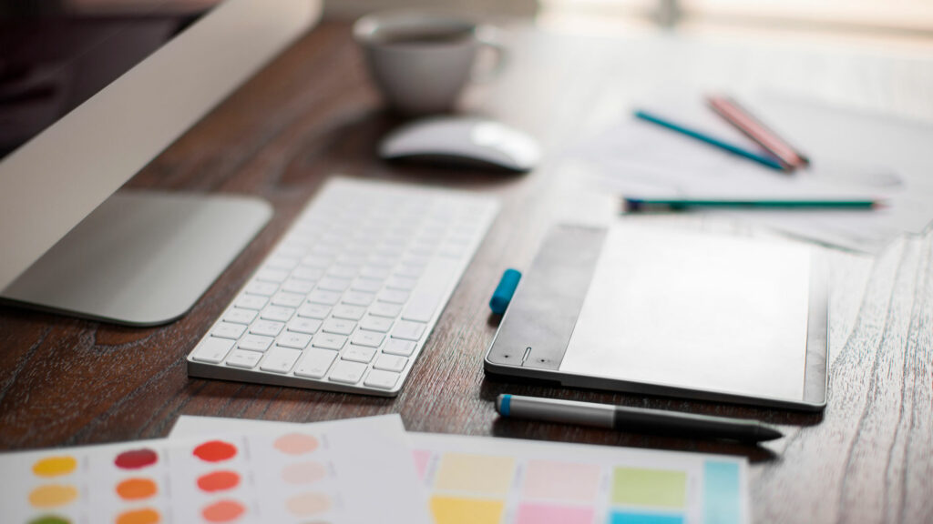 skrivebord med mac, blyanter og fargeprøver. kreativt rot med inspirasjon fra Pinterest